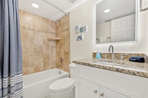 a bathroom with a granite countertop sink a toilet a mirror a bathtub and shower