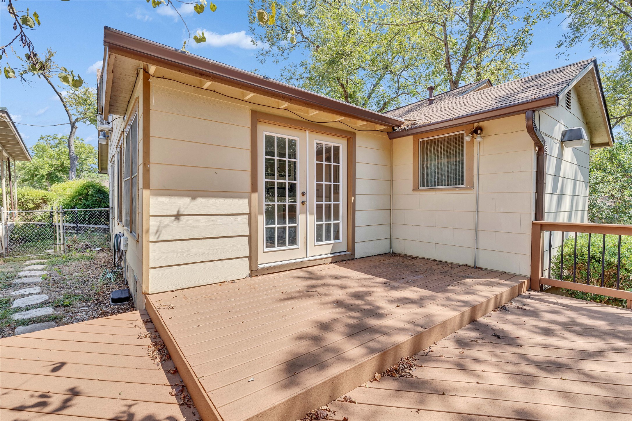 3810 Brookview Road Austin, TX 78722 - Photo 25 of 27 Double glass doors open directly onto a spacious wooden deck bordering the leafy backyard.