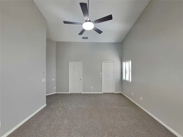 an empty room with window and ceiling fan