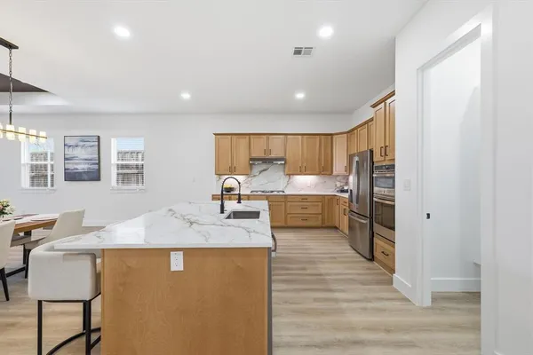a large kitchen with kitchen island a counter top space a sink stainless steel appliances and cabinets