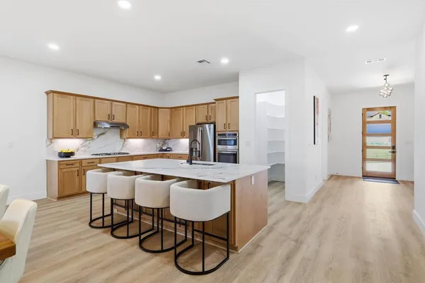 a kitchen with stainless steel appliances granite countertop a dining table chairs stove refrigerator and cabinets