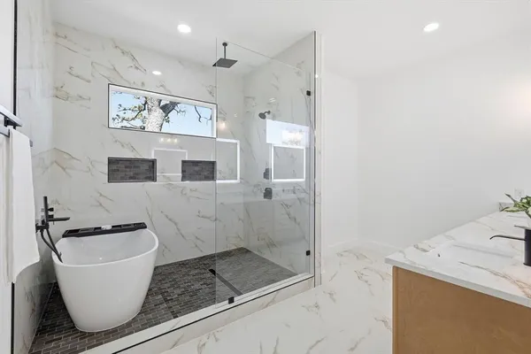 a bathroom with a granite countertop sink a mirror a bathtub and shower