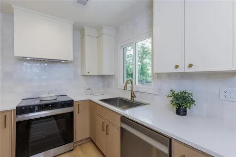 a kitchen with stainless steel appliances white cabinets and a stove top oven
