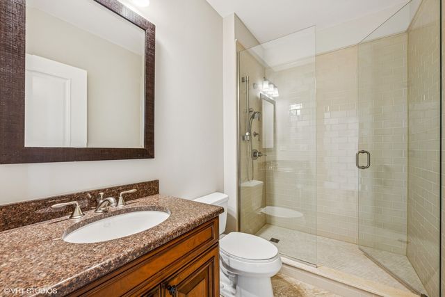 a bathroom with a granite countertop sink toilet mirror and shower