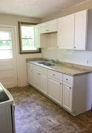 a kitchen with granite countertop a sink a stove and cabinets