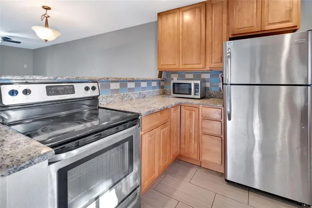 a kitchen with granite countertop a refrigerator stove and microwave
