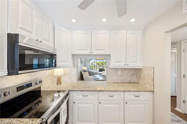 a kitchen with granite countertop white cabinets and stainless steel appliances