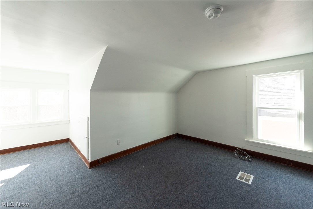 1022 North Howard Street Akron, OH 44310 - Photo 28 of 38 Another angle of 3rd floor featuring dark carpet, vaulted ceiling, wired smoke detector, and a healthy amount of sunlight
