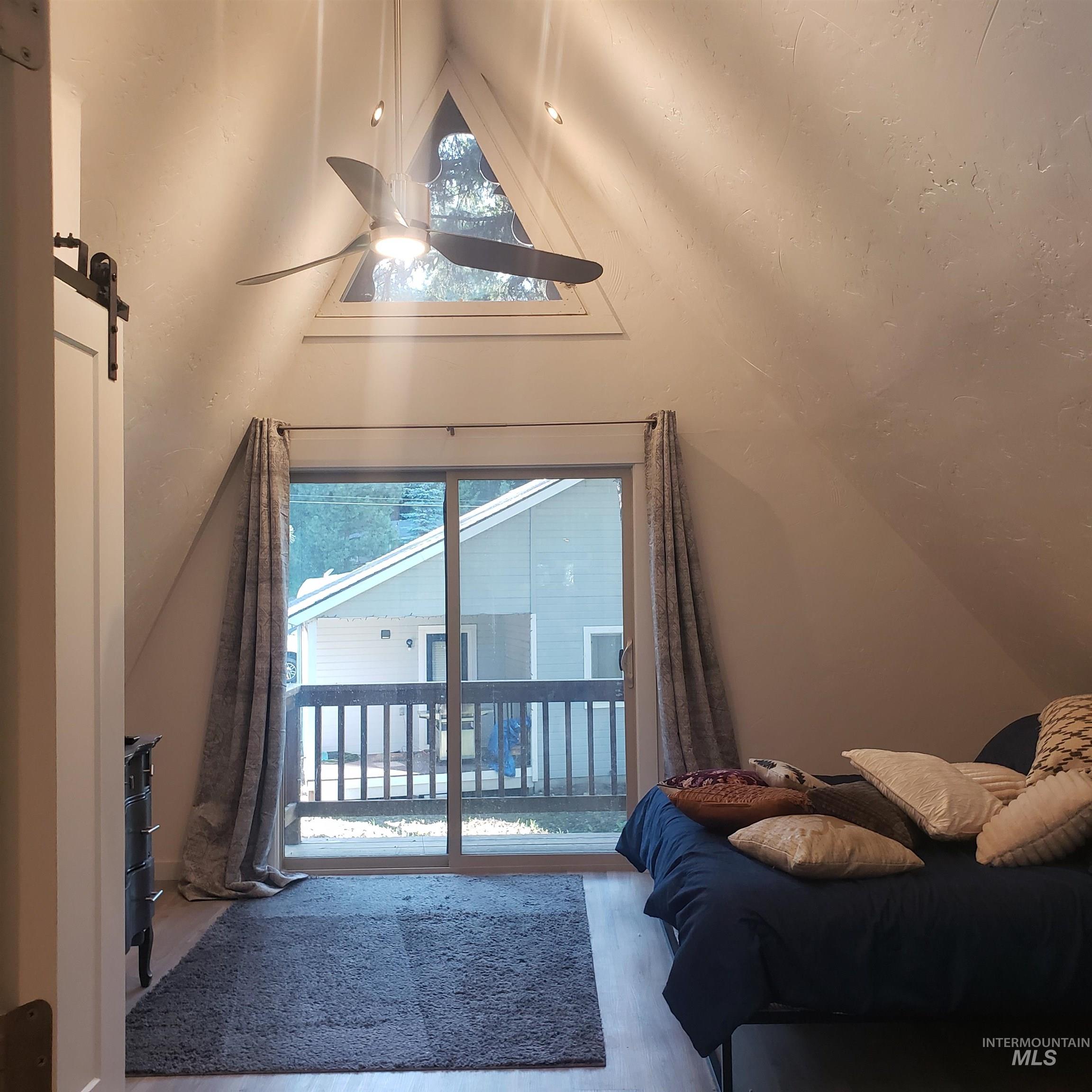 1098 Crescent Rim Drive McCall, ID 83638 - Photo 29 of 42 Bedroom with lofted ceiling, a barn door, wood finished floors, access to exterior, and multiple windows