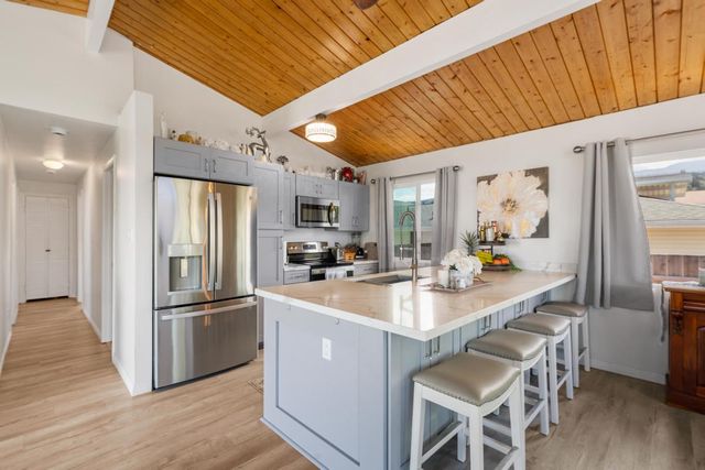 a kitchen with stainless steel appliances a sink a stove a refrigerator cabinets and wooden floor