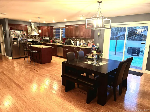 a kitchen with stainless steel appliances granite countertop a table chairs sink and cabinets