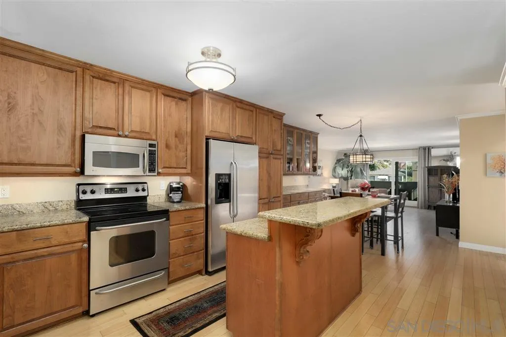 864 E Avenue Coronado, CA 92118 - Photo 7 of 20 a kitchen with stainless steel appliances kitchen island granite countertop a refrigerator a stove top oven a sink dishwasher and white cabinets with wooden floor