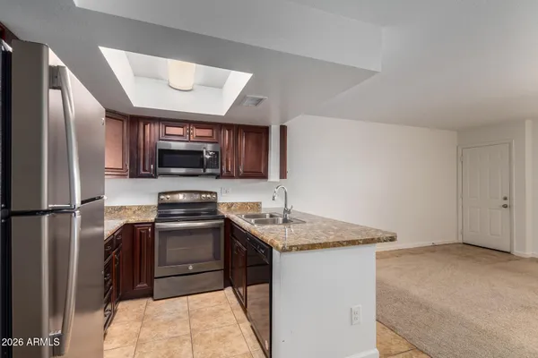 a kitchen with stainless steel appliances granite countertop a refrigerator stove a sink dishwasher and microwave