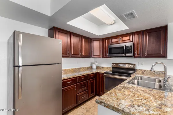 a kitchen with granite countertop a sink stainless steel appliances and cabinets