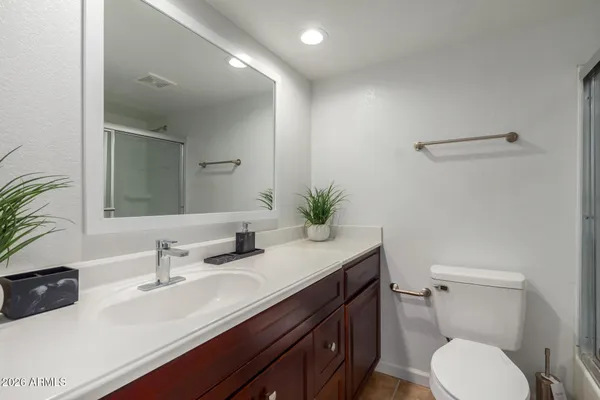 a bathroom with a granite countertop sink a toilet and shower