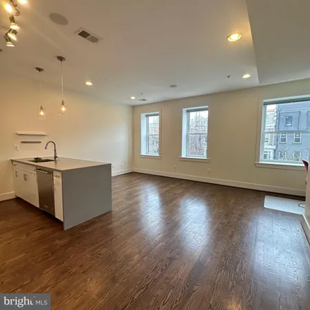 a view of an empty room with wooden floor and window
