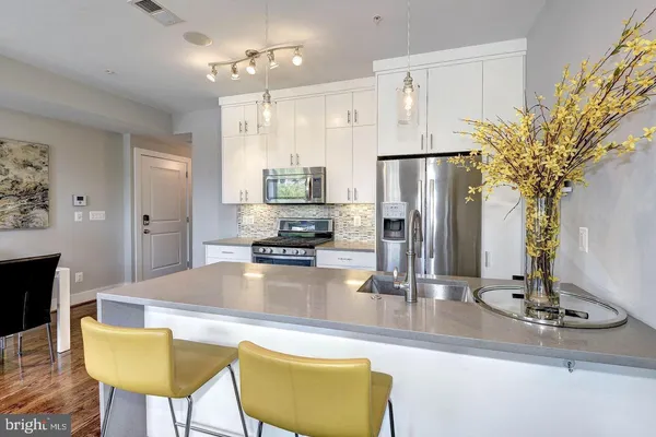a kitchen with stainless steel appliances granite countertop a table chairs and a refrigerator
