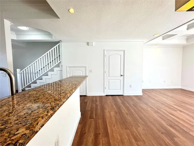 a view of a hallway with wooden floor and a bathroom