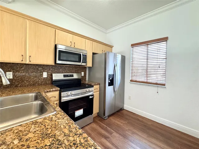 a kitchen with granite countertop a refrigerator and a stove top oven