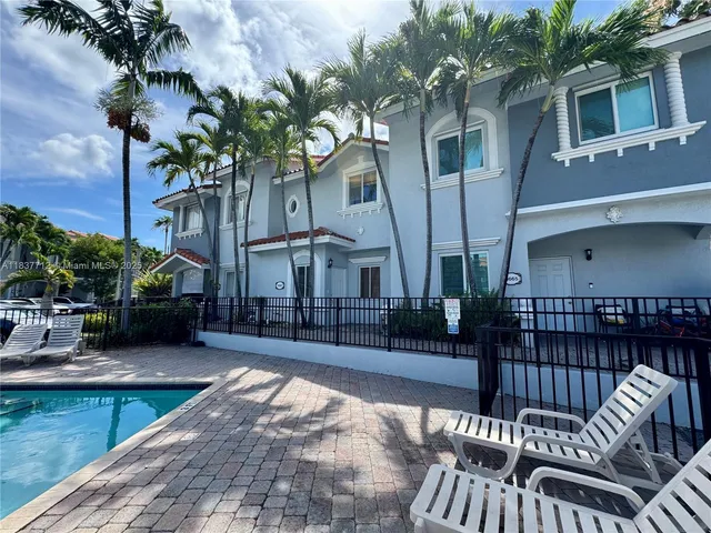 a view of a patio with couches table and chairs with potted plants and a floor to ceiling window