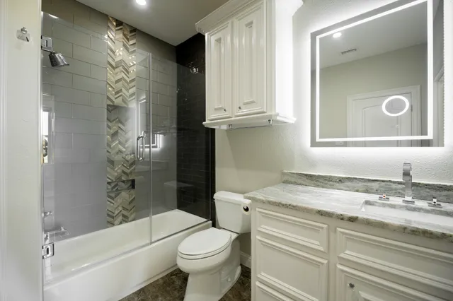 a bathroom with a granite countertop sink toilet and shower