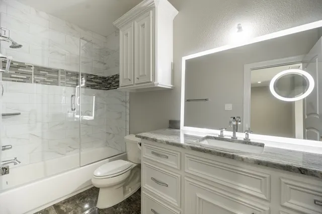 a bathroom with a granite countertop sink toilet and shower