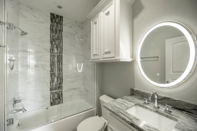 a bathroom with a granite countertop toilet a sink and a mirror
