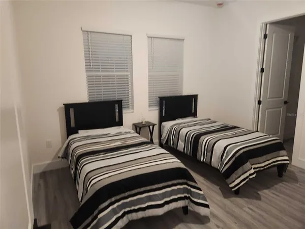 a bedroom with two beds and wooden floor