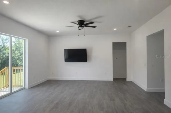 an empty room with windows and ceiling fan