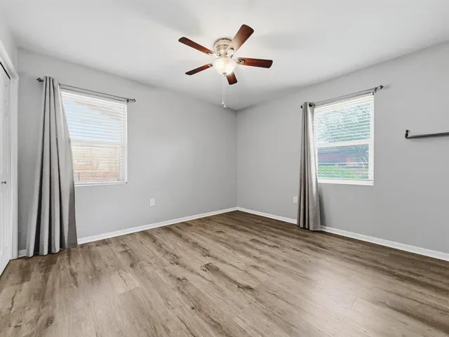 a view of an empty room with window and a ceiling fan