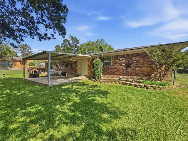 a view of a backyard with wooden fence and a large tree