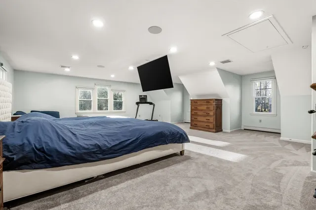 a spacious bedroom with a bed a mirror on dresser and a flat screen tv