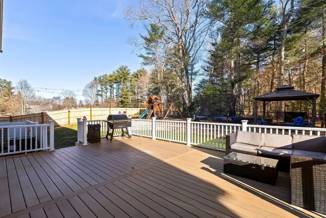 a view of a roof deck with table and chairs a barbeque with wooden floor and fence