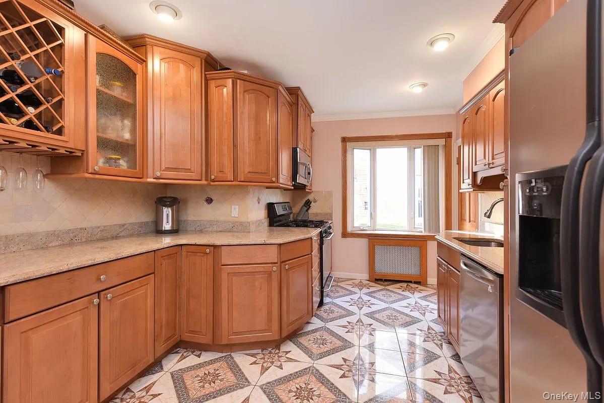 108-30 67th Avenue Queens, NY 11375 - Photo 9 of 29 a kitchen with stainless steel appliances granite countertop a refrigerator and wooden cabinets
