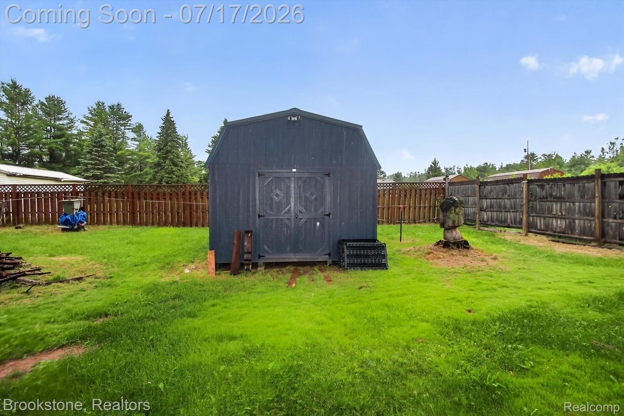 22709 Pleasant Valley Road Hillman, MI 49746 - Photo 36 of 42 Spacious backyard featuring a dark-toned storage shed with double doors, wood fencing, and mature trees along the perimeter