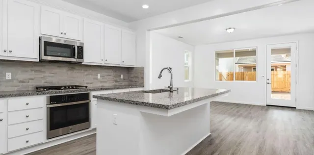 a kitchen with stainless steel appliances granite countertop a sink stove and microwave with wooden floor