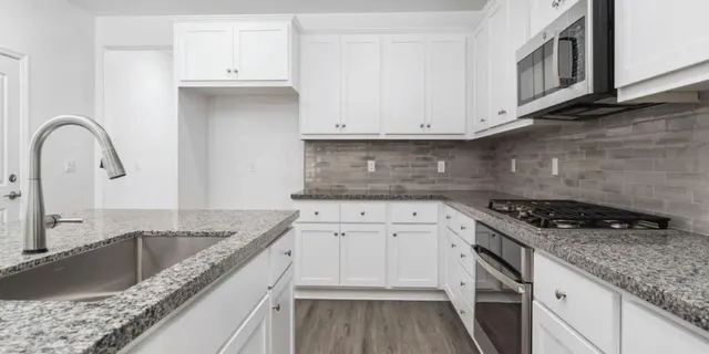 a kitchen with granite countertop a sink stainless steel appliances and cabinets