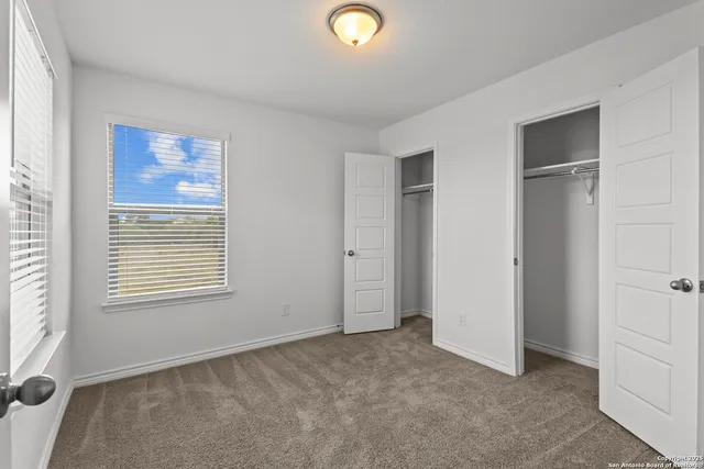 a view of an empty room with a window and dresser