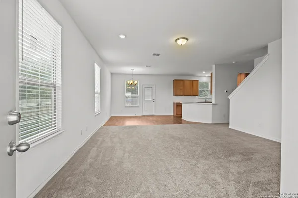 a view of a livingroom with a window and kitchen view