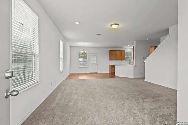 a view of a livingroom with a window and kitchen view