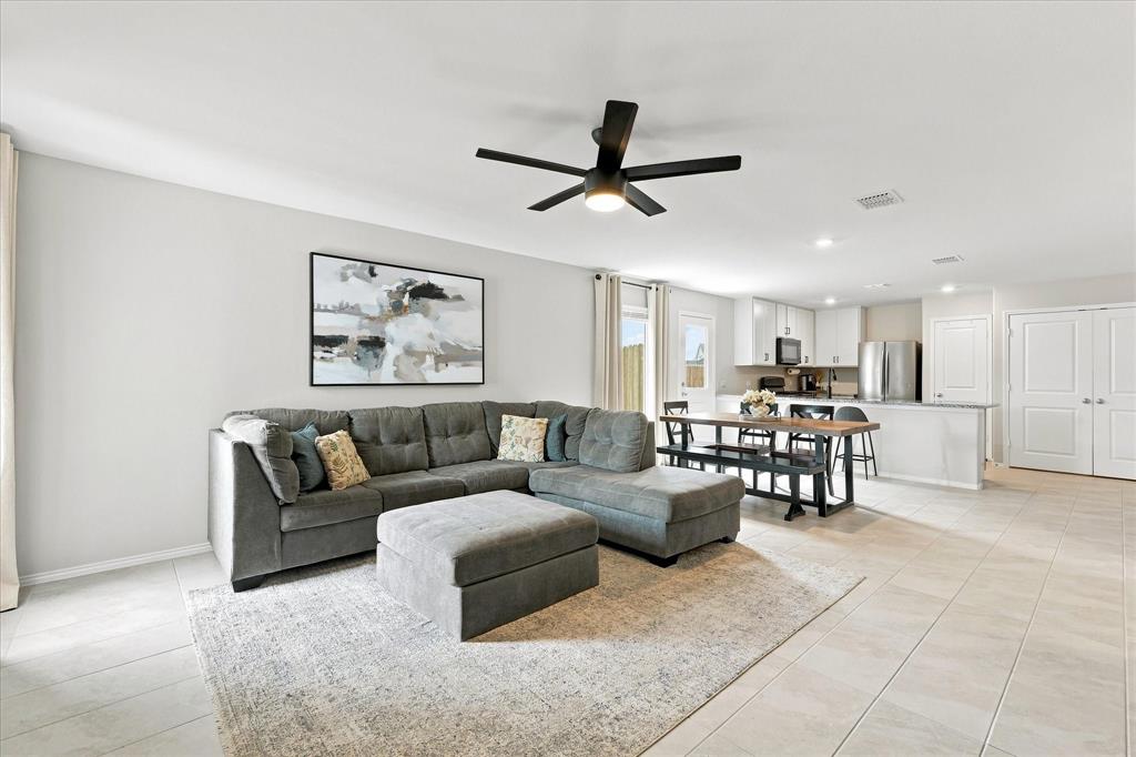 11741 Marcellus Way Rhome, TX 76078 - Photo 6 of 34 Open-concept living area with light tile flooring, a dark-finish ceiling fan, and recessed lighting