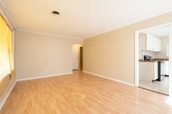 a view of an empty room with wooden floor and a window