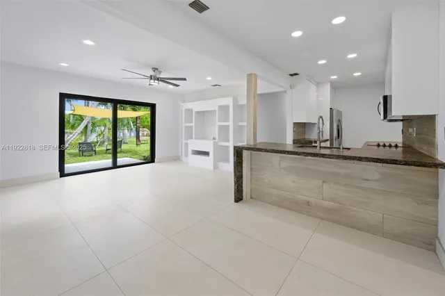 a large kitchen with kitchen island a stove a sink and a large window