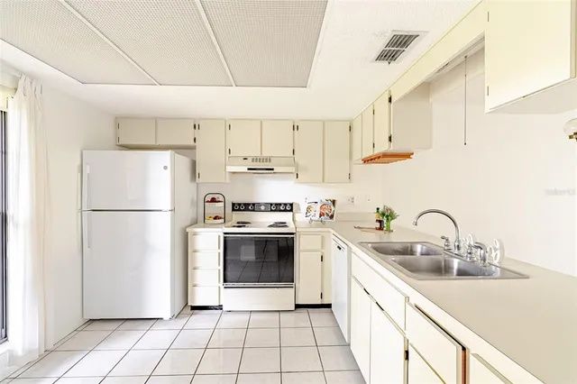 a kitchen with a sink a refrigerator and white cabinets
