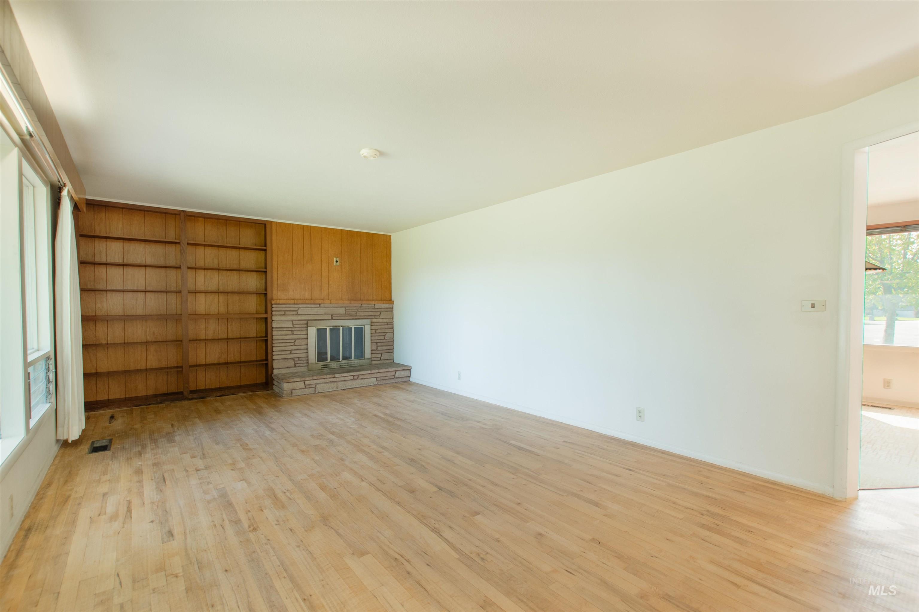 2716 North Redway Road Boise, ID 83704 - Photo 6 of 36 Hardwood flooring, stone-clad fireplace, integrated wood paneling, built-in shelving, and large windows
