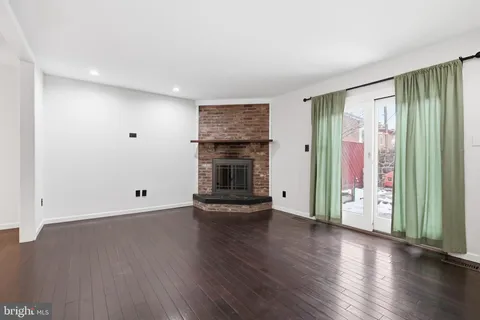 an empty room with wooden floor fireplace and windows