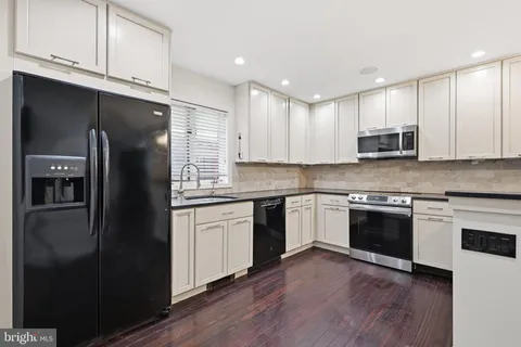 a kitchen with stainless steel appliances granite countertop a refrigerator a sink a stove a microwave and wooden cabinets