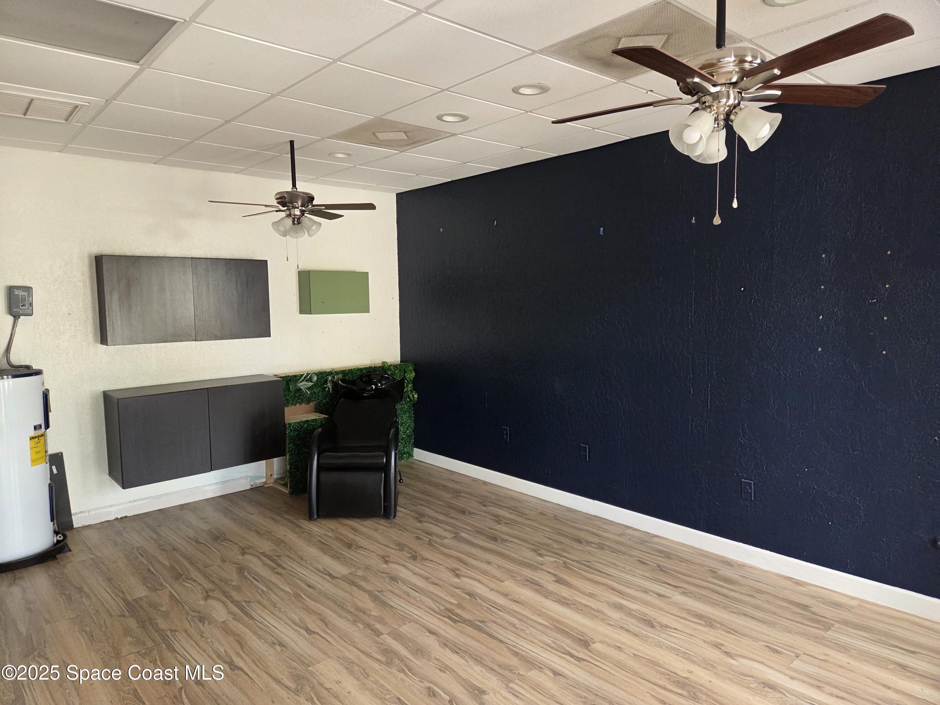 a workspace with wooden floor a chandelier fan and windows