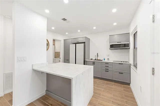 a large kitchen with kitchen island a stove a sink dishwasher and a refrigerator with wooden floor