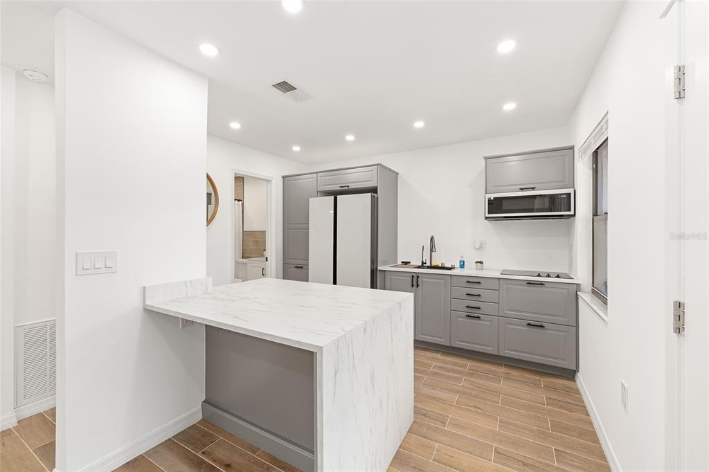 2437 Northeast 6th Street, Unit 14 Ocala, FL 34470 - Photo 12 of 22 a large kitchen with kitchen island a stove a sink dishwasher and a refrigerator with wooden floor